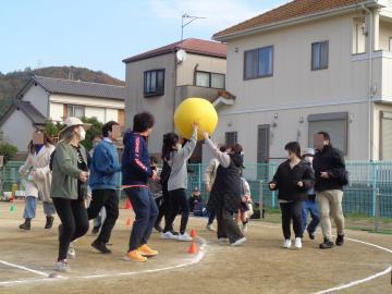 保護者の方が大玉を使ってボール送り競争をしている