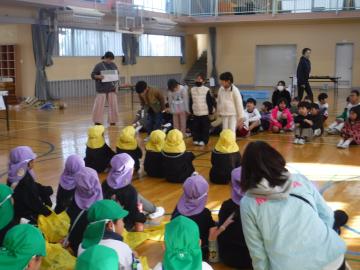 体育館で園児グループと生徒グループが向かい合って座り、生徒代表数名が立って開会のあいさつをするようす