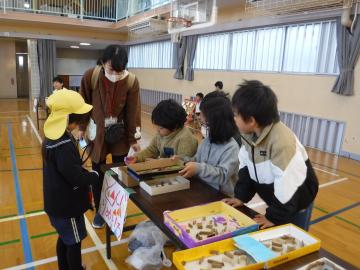 おもちゃ「どんぐり迷路」のテーブルで、生徒が園児に説明をしているようす