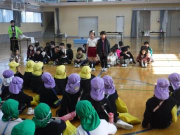 体育館で幼稚園児グループと小学生グループが向かい合って座り閉会式をするようす