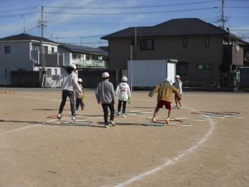 児童たちが運動場にかかれたマークに合わせてケンケンパの遊びをしている様子