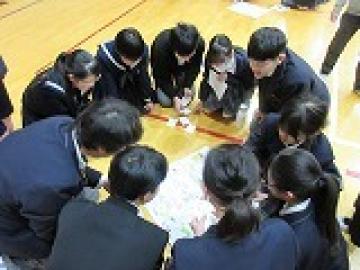 小学生が作ったカードゲームを円座になって楽しむ児童・生徒の様子