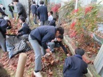 校庭の側溝の中とその周りにたまった土と落ち葉を片付ける生徒たちの様子