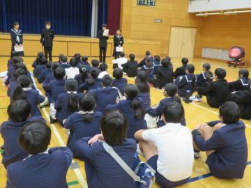 体育館内で発表会の開会挨拶をする中学生たちの様子