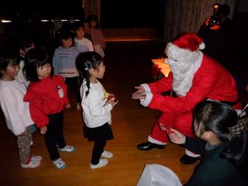 室内でサンタさんにプレゼントをもらう幼児たちの様子