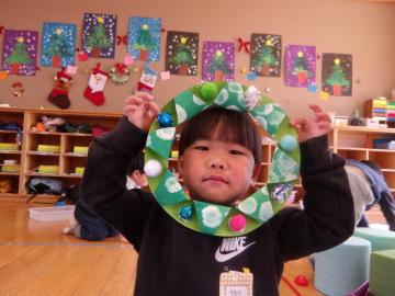 室内で3歳児がつくったリースを披露する様子