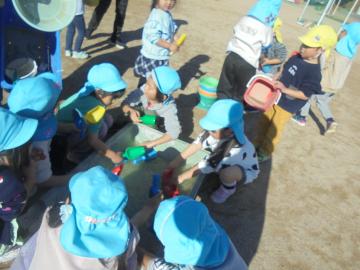 幼児が砂場の玩具を洗っているところ
