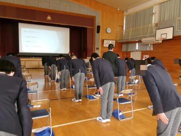 体育館で生徒が椅子の横に立ち、講師の方の指示のもと正しい礼を練習しています。