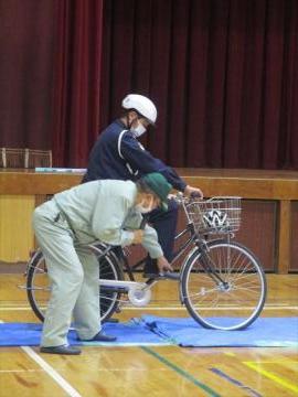 体育館で自転車に乗る前の安全点検を説明してくださる講師の様子