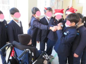 廊下に集まる児童たちの輪の中で、マイクを相手の口に近づける児童とマイクに向かってメッセージを伝える児童