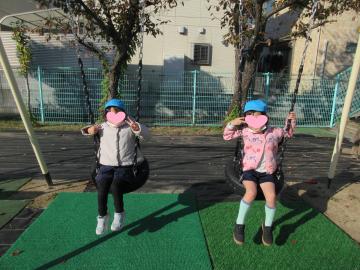 園庭で園児たちがタイヤブランコに乗っている様子