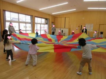 遊戯室内で園児たちがパラバルーンを膨らませている様子