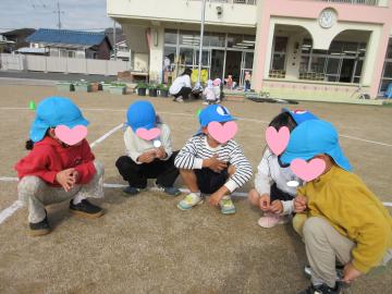 園児たちが園庭でしゃがみ、リレーの走る順番を決めている様子