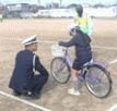 校庭で警察の方から自転車の乗り方を教わる児童の様子