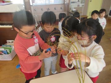 教室のテーブルに餅花を飾る4歳児