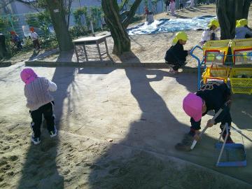 園庭の掃き掃除をする園児たちの様子