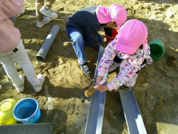 砂場のおもちゃをタワシで磨いている園児たちの様子