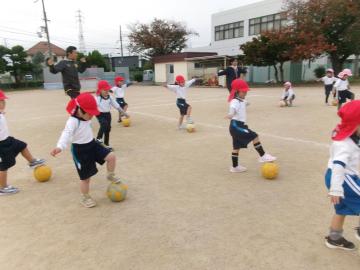 園庭でサッカー教室に参加する園児たちの様子
