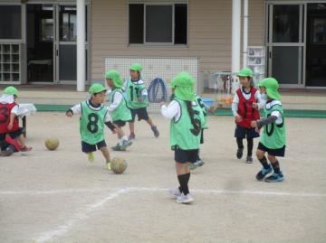 園庭でサッカーボールを蹴る園児たちの様子
