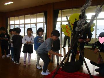 遊戯室内で吊り下げられた大きな鍋に小銭を入れて募金をする子供たち