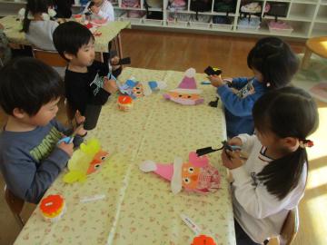 室内で画用紙でサンタクロースを作っている子供たち