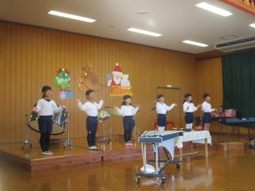 遊戯室内で手を広げて歌う子供たち