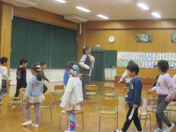 遊戯室内で椅子の周りをまわって椅子取りゲームをする子供たち