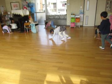 室内で床の雑巾がけをする子供たち