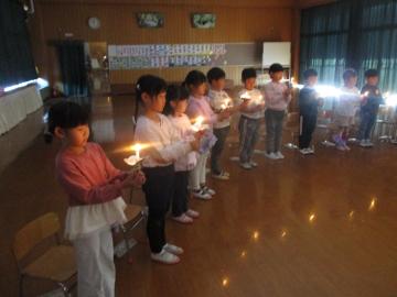 遊戯室内で一人一人ろうそくを持ってキャンドルサービスをする子供たち