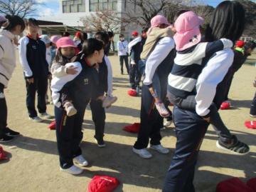園庭でおんぶをしてもらって移動している園児たちの様子