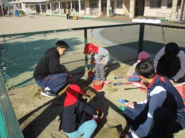 園庭で砂場遊びをしている園児たちの様子