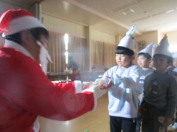 遊戯室内で、サンタさんからプレゼントをもらっている園児たちの様子