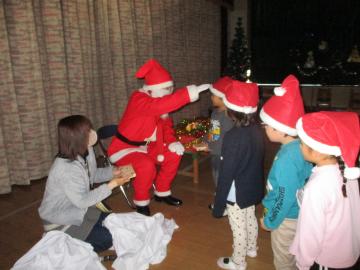 室内で園児がサンタさんからプレゼントをもらうところ