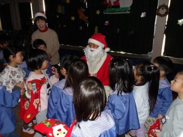 遊戯室内でサンタクロースに出会って園児が喜んでいる様子