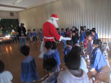 遊戯室内でサンタクロースに頭をなででもらっている園児たちの様子