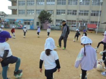 校庭でサッカーの指導を受けている園児たちの様子