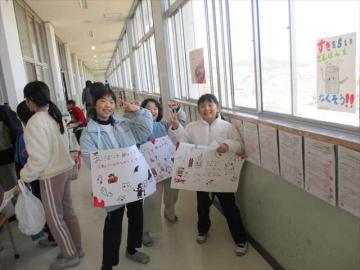 廊下でお客さんを呼ぶために看板を持っている児童たちの様子