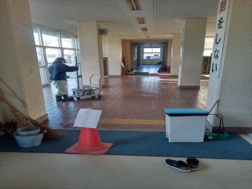 用務員さんが生徒玄関を掃除している様子