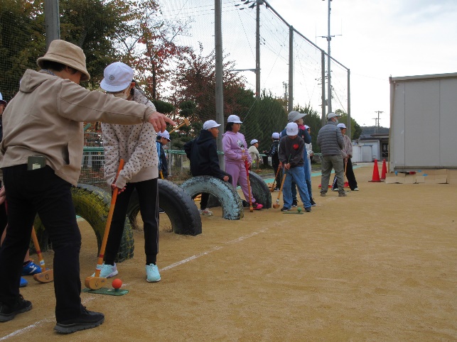 子どもたちが地域の方とグラウンドゴルフを学ぶ様子