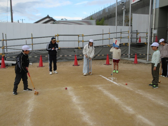 子どもたちが運動場で地域の方とグラウンドゴルフを楽しむ様子
