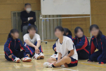 ゲームの間に体育館の床に座って談笑する生徒です。