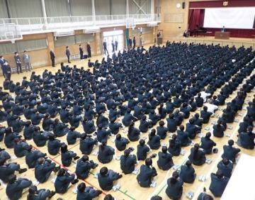 体育館に整列して座る生徒が始業式で話を聞く様子
