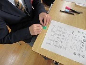 着席し、折り方の手順を見ながら折り鶴を折る生徒の手元の様子
