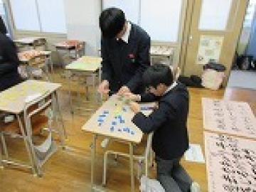 教室内で折り鶴に糸を通す男子生徒の様子