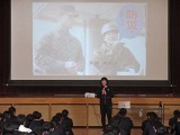 体育館でスライドをもとに話をする講師先生の様子