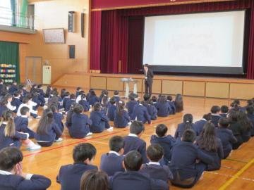 体育館内で1月の月目標についての話を聞く全校生の様子