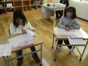 教室の自分の席で書初めをする2年生