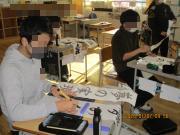 教室の自分の席で書初めをする6年生たち