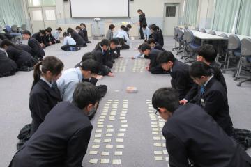 正座をした7年生が床に並べた目の前のカルタに集中している様子