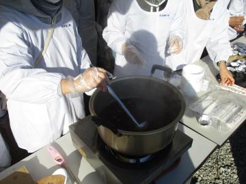 大きな鍋でぜんざいを作る人が鍋を混ぜている様子